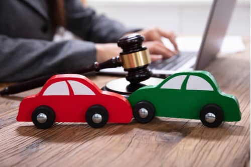 Lawyer working on laptop next to model cars, Boise car accident lawyer concept