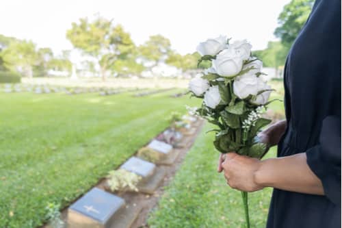 Woman holding white roses at grave, Boise wrongful death lawyer concept